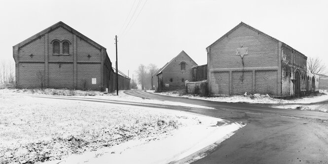 Schwarz-weiße Sicht auf zwei alte Backsteinscheunen im Schnee