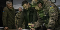 Der ukrainische Präsident Wolodymyr Selenskyj und drei weitere Männer in Militärkleidung betrachten eine Landkarte.