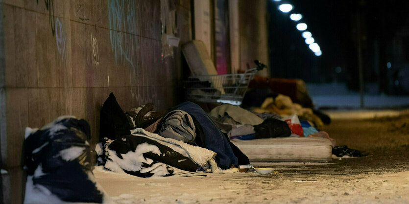 An einer Hauswand liegen Matrazen und Decken im Schnee, als Nachtlager für Obdachlose.