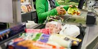 Eine Supermarkt Kassiererin zieht Waren übers Band