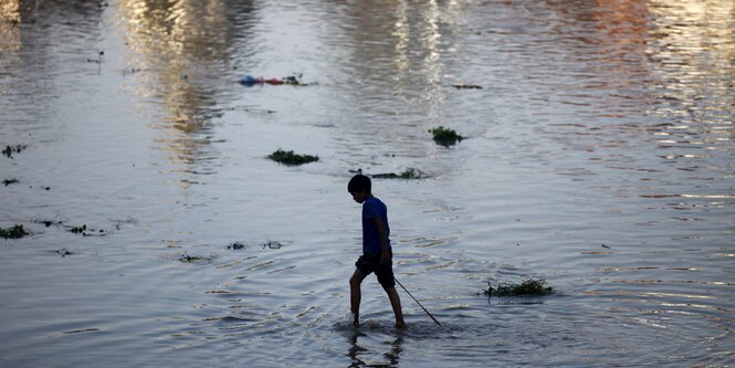 Junge, der durch ein Fluss watet.