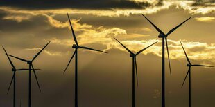 Silhouetten von Windrädern bei Sonnenuntergang