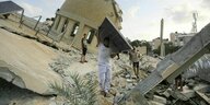 Ein Mann trägt ein Solarpanel vor einer zerstörten Moschee