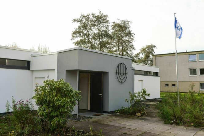 Aussenaufnahme der Synogoge in Pinneberg, ein heller Flachdachbau auf dem eine israelische Flagge weht