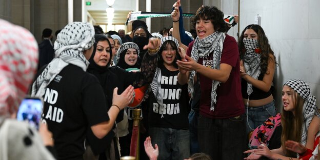 Junge Menschen mit Palästinenser-Tüchern diskutieren miteinander
