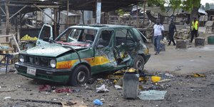 Ein bei einem Terroranschlag zerstörtes Auto steht auf einem Marktplatz in Maiduguri, Nigeria.