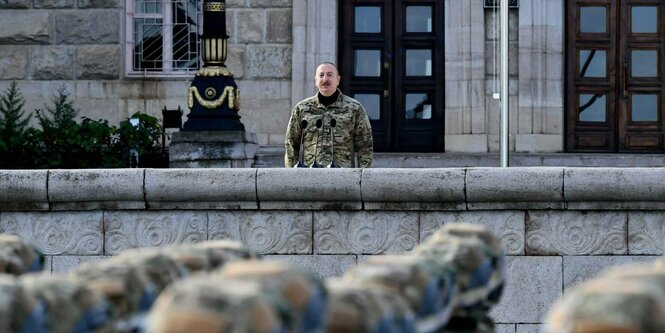 Ein Mann in Militärkleidung beobachtet eine Militärparade.