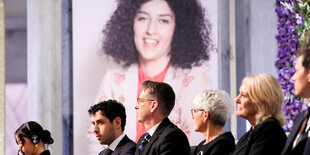 Ein Foto von Narges Mohammadi bei der Preisverleihung. Davor ihre Kinder Ali und Kiani Rahmani