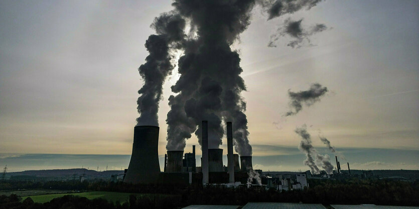 Blick auf ein Kraftwerk mit rauchenden Kühltürmen