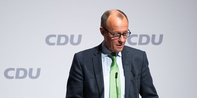 Friedrich Merz vor einer Wand, auf der das parteilogo der CDU abgebildet ist