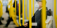 Eine Person mit Maske sitzt in einer U-Bahn