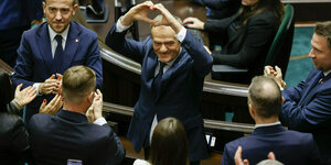 Donald Tusk steht im Parlament und formt mit seinen Händen eine Herz
