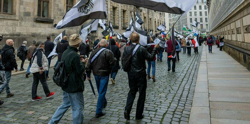 Menschen protestieren auf einer Straße mit Fahnen des Königreichs Preussen