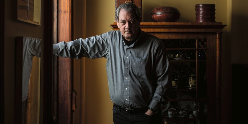 Paul Auster lehnt seinen Arm an ein Fenster