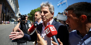 Argentiniens Wirtschaftsminister Luis Caputo wird von Reportern mit Mikrophonen umringt