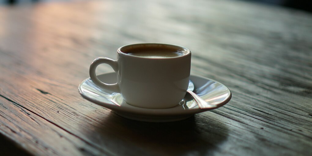 Eine gefüllte Kaffeetasse steht auf einem Holztisch.