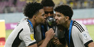 Drei deutsche Fußballnationalspieler küssen den WM-Pokal