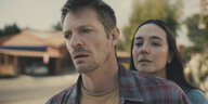 Brian Godlock (Joel Kinnman) und seine Frau Saya (Catalina Sandino Moreno) stehen in einer Wohnsiedlung auf der Straße.