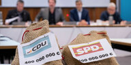 Zwei Säckchen, auf denen «CDU 400.000.000 €» und «SPD 400.000.000 €» steht, liegen während eines Pressegesprächs zum Berliner Doppelhaushalt 2024/25 auf einem Tisch. Die Säcke hatte ein TV-Redakteur zur Illustration des Themas mitgebracht.