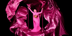 Wie ein Madonnenbild: Nicki Minaj in pinkem Kleid in einer riesigen pinken Schleppe, vor schwarzem Hintergrund