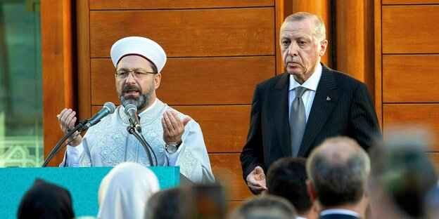 Recep Tayyip Erdogan steht neben einen Imam auf einer Bühne