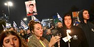 Menschen halten brennende Kerzen und Schilder mit Fotos der von der Hamas entführten Menschen