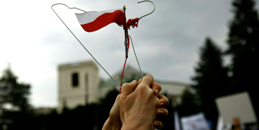 Eine Frau hält einen Kleiderbügel mit der polnischen Flagge in der Hand