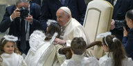 Papst Franziskus mit Kindern als Engel verkleidet.