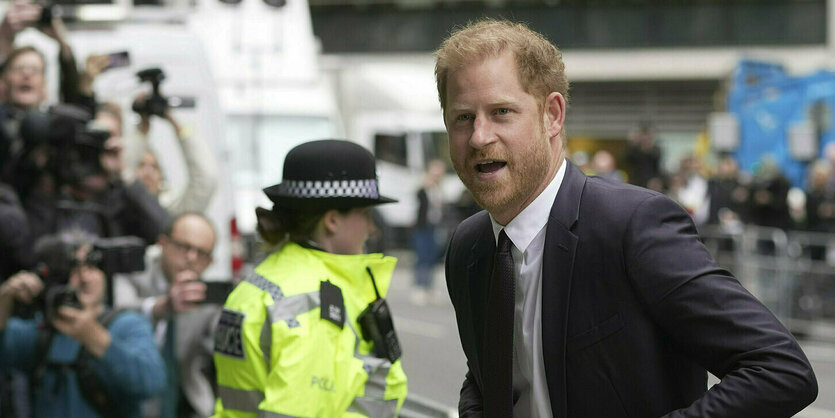 Prinz Harry mit Fotografen im Hintergrund.