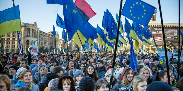 Junge Menschen demonstieren mit EU-Flaggen und Ukraine-Flaggen auf einem großen Platz.