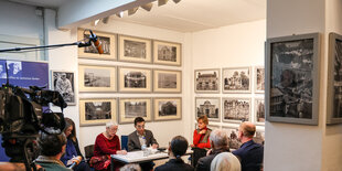 Ein kleiner Raum mit s-w-Fotos an der Wand, Publikum, dahinter Podium mit Masha Gessen in der Mitte, Kameras und Mikros sind auf das Podium gerichtet