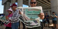 Männer lesen Zeitungen, auf denen ein Zug und der Titel "Tren Maya" zu sehen ist