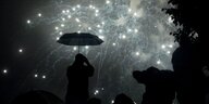 Mann mit Schirm unter Feuerwerk