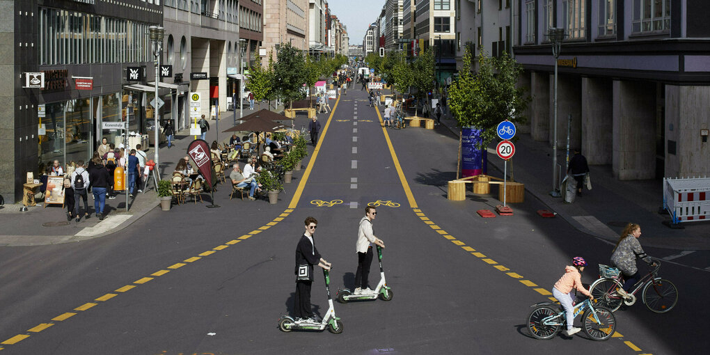 Roller und Fahrräder überqueren die autorfreie Friedrichstraße