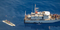 Ein Floß auf dem Mittelmeer daneben ein Schiff der Libyschen Küstenwache