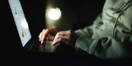 Eine Person sitzt im Dunkeln vor einem Laptop