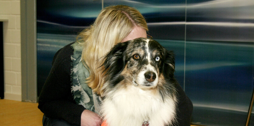 Eine junge blonde Frau versteckt sich hinter einem Hund