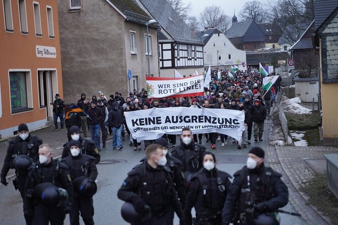 Menschen laufen mit Transparenten durch ein Dorf