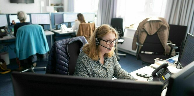 Personen sitzen in einem Büro und geben telefonisch Auskunft