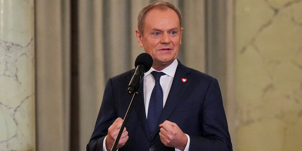 Donald Tusk steht vor einem Mikrofon und ballt die Fäuste