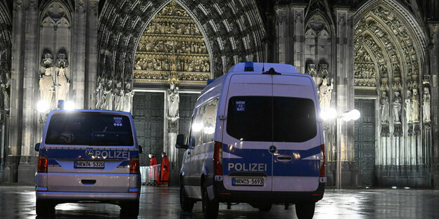 Polizisten kontrollieren am Eingang des Kölner Doms den Beginn der Frühmesse am Weihnachtstag