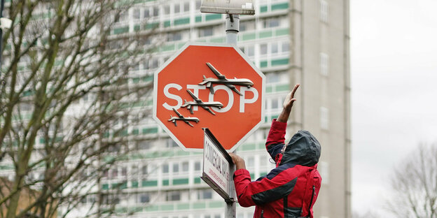 Ein Mann macht sich an dem Stoppschild in London zu schaffen, auf dem drei Drohnen zu sehen sind