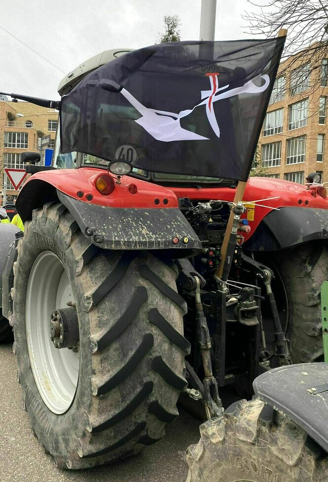 An einem Traktor befestigte Flagge: auf schwarzem Untergrund ein wiesser Pflug und rotes Schwert