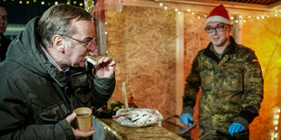 Boris Pistorius (SPD), Bundesminister der Verteidigung, beißt auf dem Weihnachtsmarkt neben Bundeswehrsoldaten in einen Christstollen