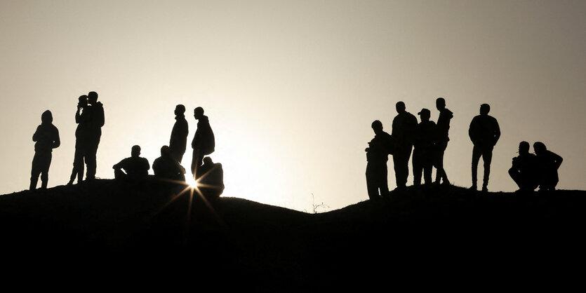 Eine Gruppe von Palestinensern am Rande einer Beerdigung steht im Gegenlicht im Süden des Gazastreifen