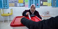 Eine Frau mit Kopftuch wirft ihren Wahlzettel in eine Wahlurne