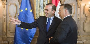 Martin Weber zeigt lächelnd nach rechts, Orbans Blick folgt