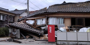 Ein zur Häfte eingestürztes Haus, davor ein Getränkeautomat