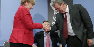 Angela Merkel schüttelt Gerhard Schröder die Hand.