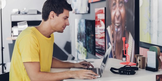 Ein junger Mann sitzt an einem Laptop